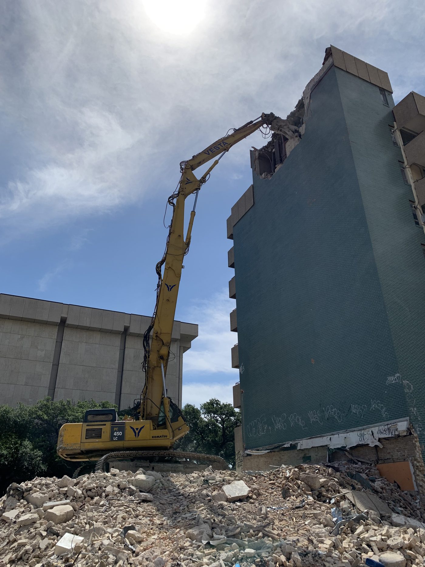 High-reach excavator demolishing a downtown Austin tower on Guadalupe Street